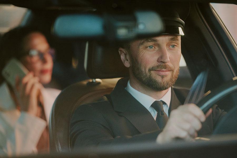 Professional chauffeur driving with passenger